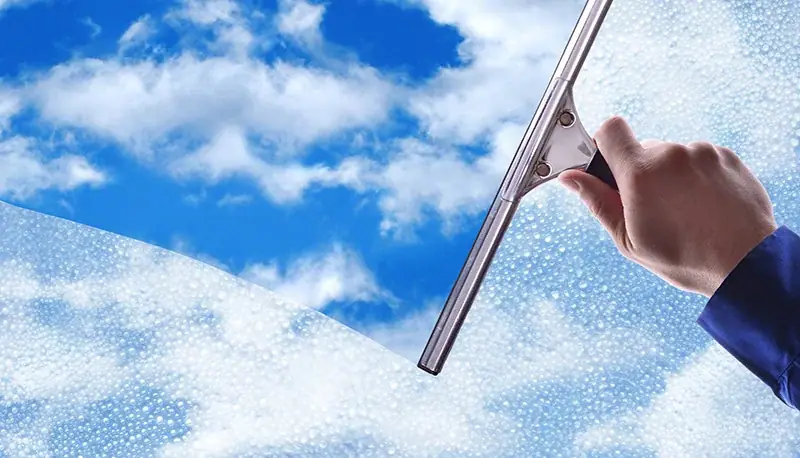 Fensterreiniger zieht eine Glasfläche mit dem Abzieher streifenfrei ab